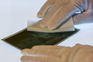 gloved hands cleaning a photo negative